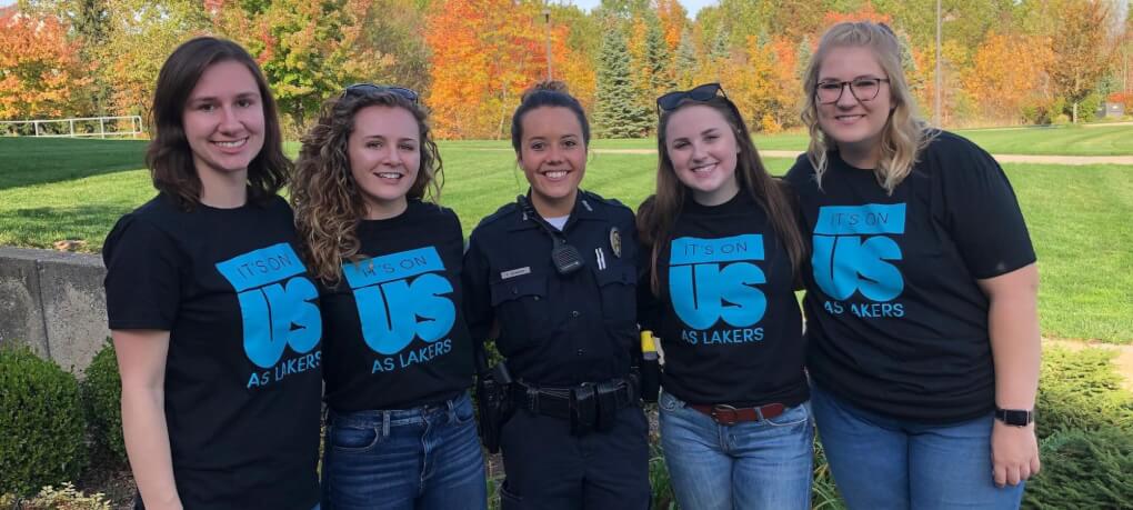A female GVPD officer stands with female students wearing "Its on us" shirts